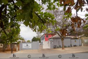 a building with a red house in the distance at Blooming Rose Bed and Breakfast in Polokwane