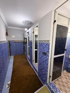 a room with blue tiled walls and a walk in shower at Gite Souran Imsker in Tagadirt Aït Ali