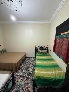 a bedroom with two beds and a rug at Gite Souran Imsker in Tagadirt Aït Ali