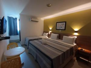 a hotel room with two beds and a table at Pousada Maragolfinho in Maragogi