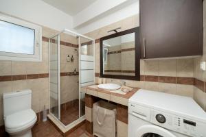 a bathroom with a toilet sink and a washing machine at Naria Home by A&D Properties in Porto Rafti