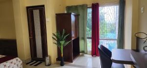 a living room with a plant in front of a window at Hotel Roy's in Shādipur