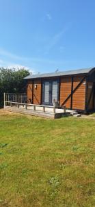 a large wooden cabin with a grassy field in front of it at Pen-Rhos luxury glamping "Cuckoo's Nest" in Llandrindod Wells