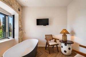 a bathroom with a tub and a chair and a television at Hotel Heritage Casa Blanka in Makarska