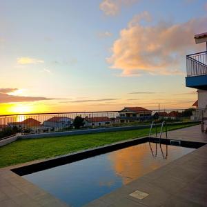 a swimming pool with a sunset in the background at Sunset Cottage - Special Places in Ponta do Pargo