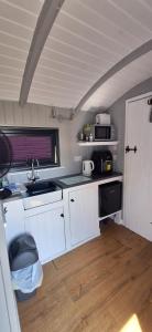 a small kitchen with white cabinets and a sink at Pen-Rhos luxury glamping "Cuckoo's Nest" in Llandrindod Wells