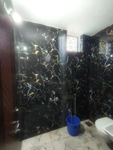 a black tiled bathroom with a shower and a toilet at Farmview Guest House Netravali in Netorlim +23 photos