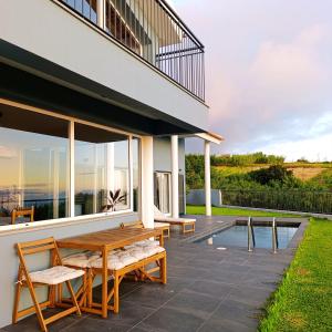a patio with a wooden table and chairs next to a building at Sunset Cottage - Special Places in Ponta do Pargo