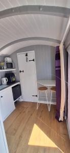 a room with a door and a table and a kitchen at Pen-Rhos luxury glamping "Cuckoo's Nest" in Llandrindod Wells