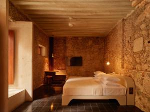 a bedroom with a bed in a stone wall at Hotel Sevilla, a Member of Design Hotels in Mérida +38 photos