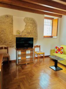 a living room with a tv and a stone wall at Mirella house Desenzano del Garda -Centro storico, 30 mt dal lago in Desenzano del Garda +15 photos