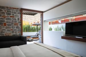 a room with a bed and a tv and a couch at La Purificadora, Puebla, a Member of Design Hotels in Puebla
