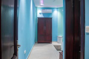 a hallway with blue walls and a wooden door at Bralph-k in Yaoundé