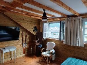 a bedroom with wooden walls and a tv and a chair at Maison d'Hôtes L'Intemporelle in Bagnères-de-Bigorre
