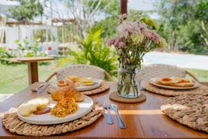a wooden table with plates of food and a vase of flowers at Tiny Village Cartagena Boutique Resort in Tierra Bomba