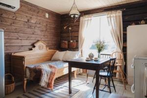 a bedroom with a bed and a table and a window at Cozy forest cabin with wood-fired sauna in Naantali