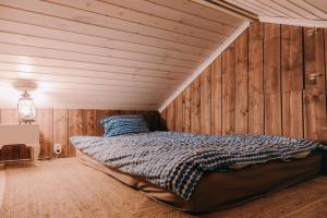 a bed in a room with wooden walls at Cozy forest cabin with wood-fired sauna in Naantali