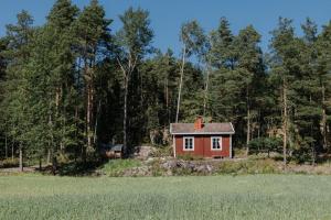 a small red house in the middle of a field at Cozy forest cabin with wood-fired sauna in Naantali