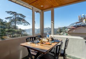 a dining room with a table and chairs and windows at Hotel Windsor in Shimla