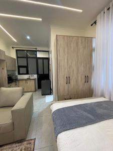 a bedroom with a bed and a couch and a kitchen at Tulia, Anchor in Ruaka