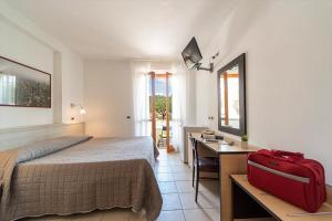 a bedroom with a bed and a desk with a red suitcase at Residence Hotel Villa Mare in Portoferraio