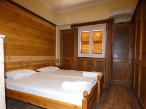 two beds in a room with wooden walls and a window at Iona Achilleion Appartments in Achílleion