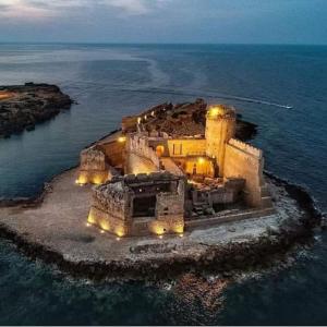a building on an island in the water at night at B&B Florida sul mare via faro 30 in Capo Rizzuto +24 photos