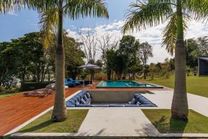a swimming pool with two palm trees in a yard at Casa a jabuticabeira in Avaré +1 photo