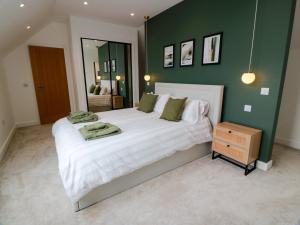 a bedroom with a large white bed with a green wall at Balcarry Barn in Newton Stewart