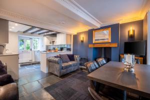 a living room with a table and a kitchen at Ross Cottage in Hawkshead
