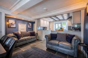 a living room with two couches and a kitchen at Ross Cottage in Hawkshead