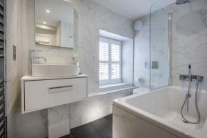 a white bathroom with a tub and a sink and a bath tubermott at Ross Cottage in Hawkshead +25 photos