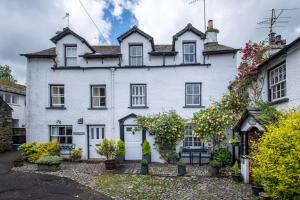 an exterior view of a white house with flowers at Ross Cottage in Hawkshead