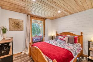 a bedroom with a bed with red sheets and a window at Le Boreal in Pohénégamook +61 photos