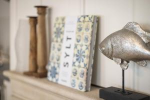 a fish statue on a shelf next to a book at Strandkrabbe in Keitum