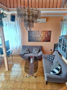 a living room with two couches and a chandelier at Sylvia Apartman in Balatonalmádi