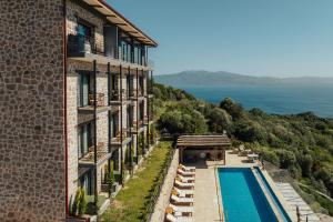 a building with a swimming pool next to the ocean at Serotonin Premium Collection in Balabanlı