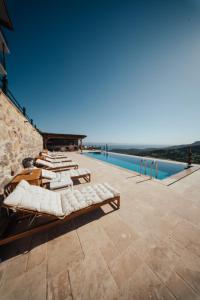 a row of chaise lounges on a patio next to a pool at Serotonin Premium Collection in Balabanlı
