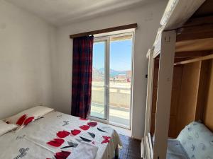 a bedroom with a bed and a large window at Old Saranda Apartments in Sarandë