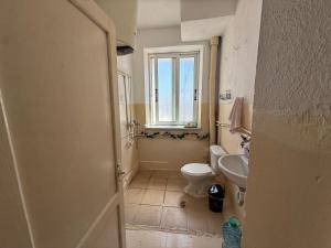 a bathroom with a toilet and a sink and a window at Old Saranda Apartments in Sarandë