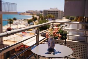 a vase with flowers sitting on a table on a balcony at Zoe Apartment Port View Β in Rafina