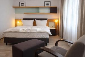 a bedroom with a large bed and a chair at Check-Inn Hotel - free parking in Offenbach +12 photos