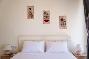a bedroom with a white bed with three pictures on the wall at Zoe Apartment Port View Β in Rafina
