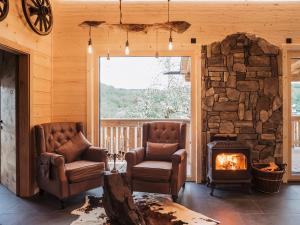 a living room with two chairs and a stone fireplace at Romantikchalet Bärenhöhle mit eigenen Wellnessbereich, Komfort und viel Ruhe in Vorra