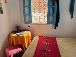 a room with two beds and a table and a window at Le Retour au calme Maison d'hôtes in Tinerhir +84 photos