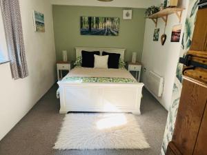 a bedroom with a white bed with two night stands at The Old Cowshed - B and B in Pembroke