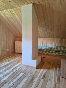 a bed in a room with wooden floors and wooden ceilings at Domek Góra Gbura in Ulucz