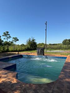 a swimming pool with blue water in a yard at Quinta Rojas Riveros in Encarnación