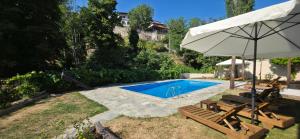 a swimming pool with an umbrella and some chairs and a table at Triantafillies Traditional Hotel in Portaria