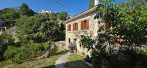 an old stone house with plants on the side of it at Triantafillies Traditional Hotel in Portaria